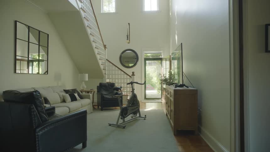 Interior of a home with a seating area couches exercise bike television and staircase