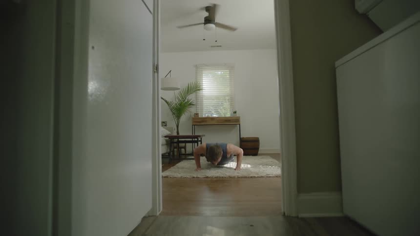 A man is doing push ups on a white rug at home