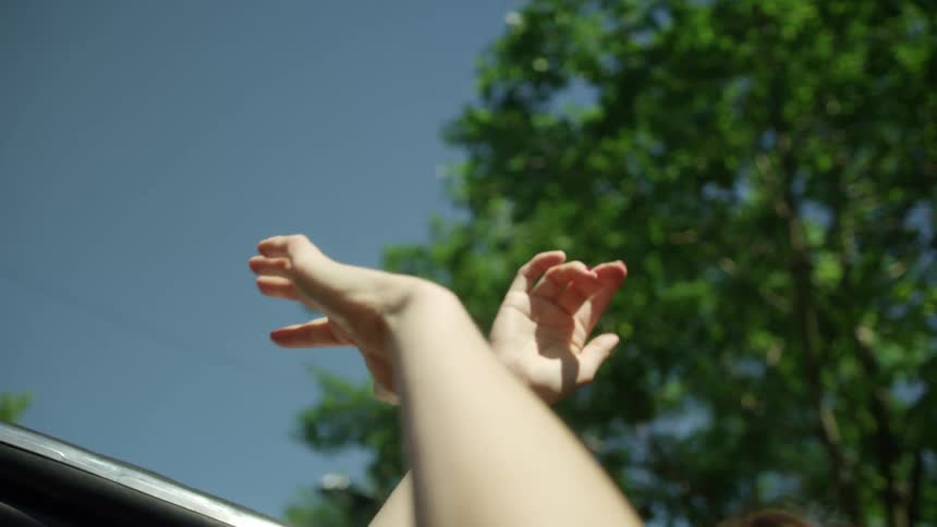 A woman outside moves her arms as they are raised in the air