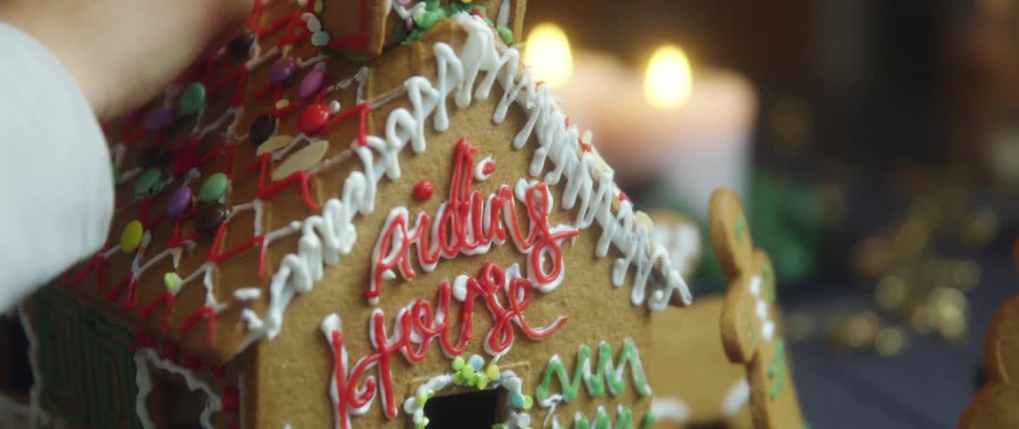 Young boy decorating a gingerbread house with candy