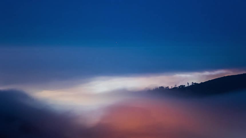 Time lapse of clouds passing over a city in a valley on the mountains at sunset