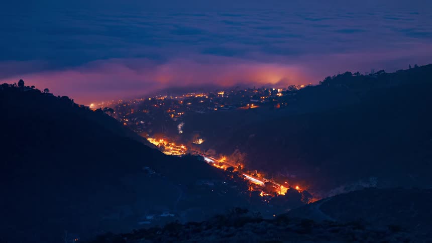 A highway with traffic between two hills with sped up time to show morning to night