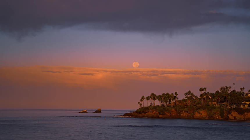 Time lapse of night to day of a landscape body of water and moon in the sky