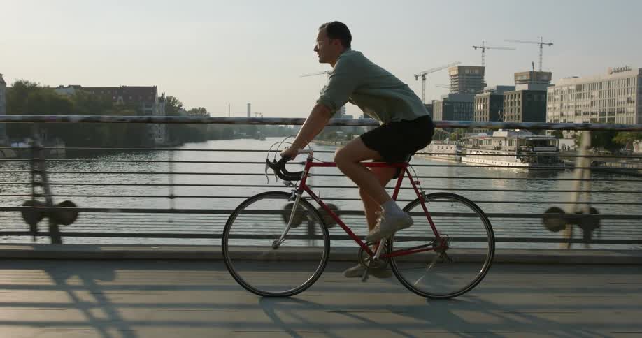 A man bikes across a bridge in a city
