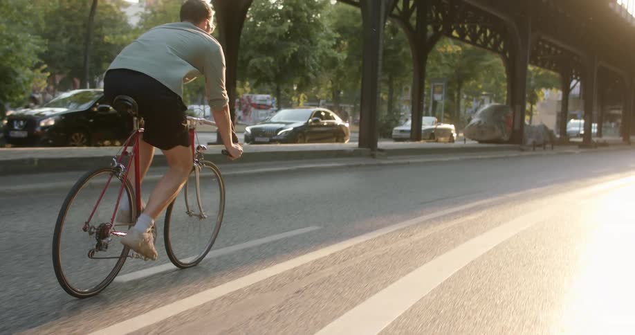Man riding a bicycle on a road in the city at sunset