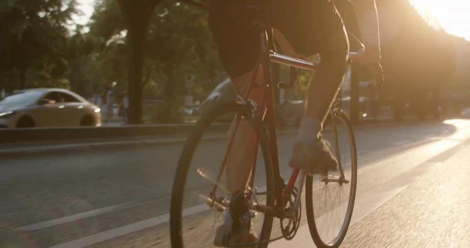 A man is riding a bicycle on a paved road in a city