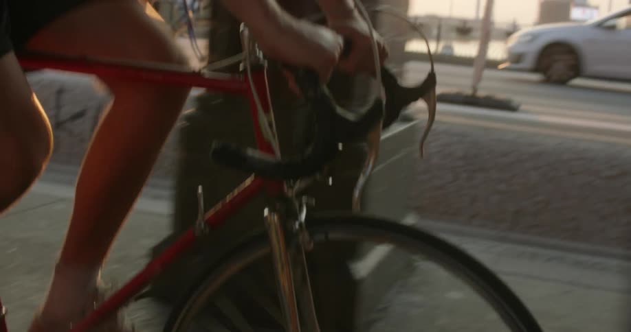 Two cyclists ride bicycles on the street of a city at sunset