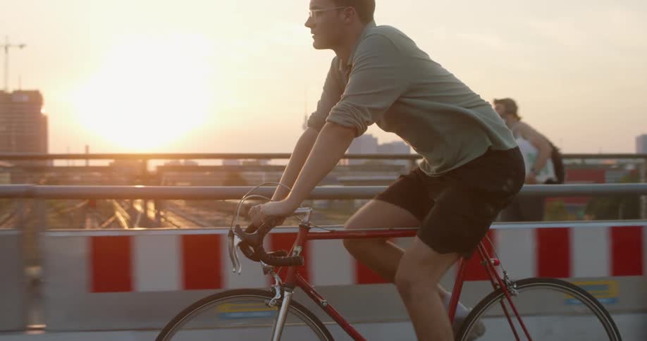 A man cycles across a bridge with pedestrians walking on it