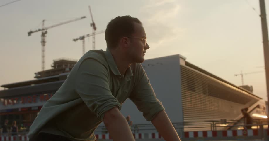 A man turns his head and looks at the setting sun while riding his bike