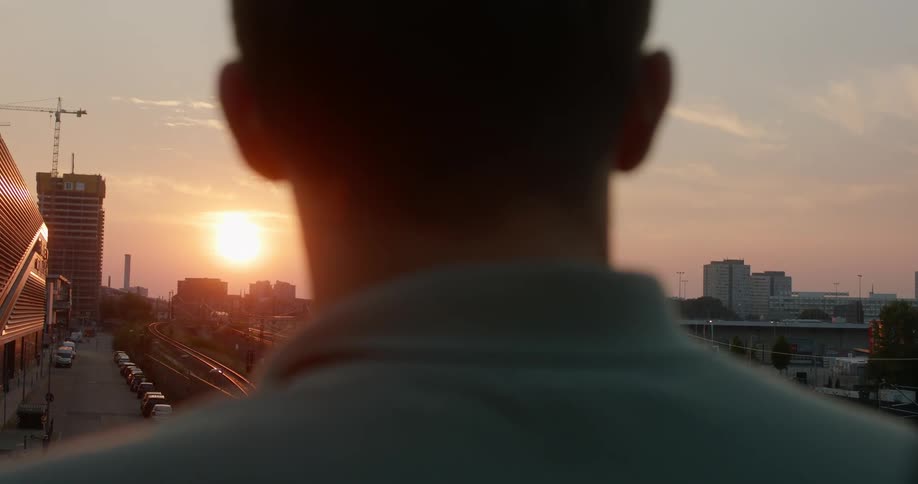 Silhouette of a mans head looking at the sunset over the city