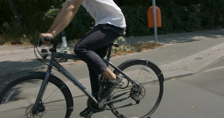 A young man rides a bicycle down a street through a neighborhood during the day