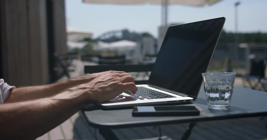 A man is typing on his laptop outside