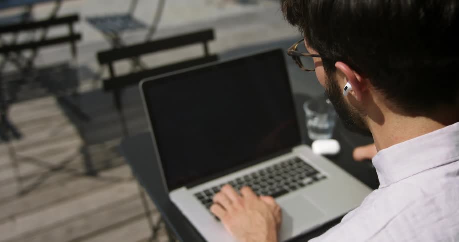 A man is outdoors with his laptop and phone