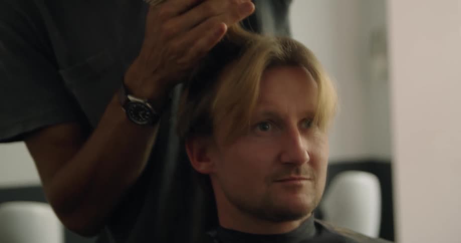 A hair stylist talks to a customer while combing and cutting the the customers hair