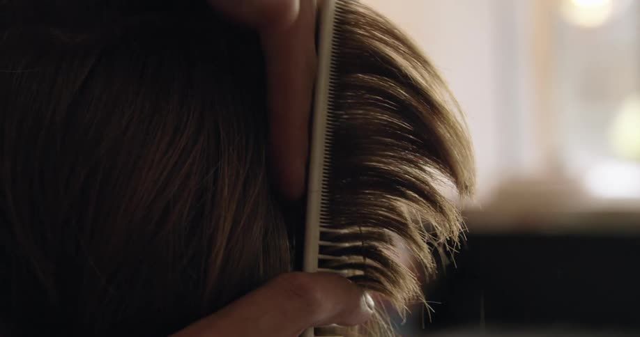 A stylist cutting the hair of a customer using a comb and scissors