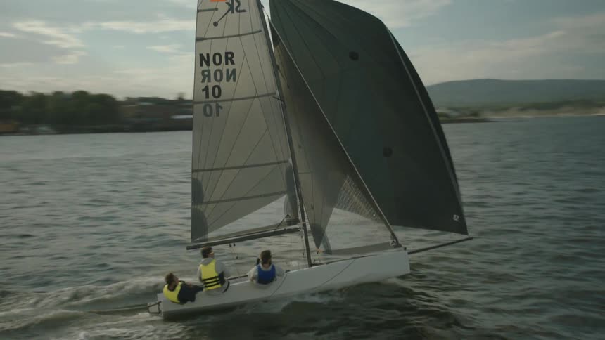 Three men ride on a sailboat on a sunny day