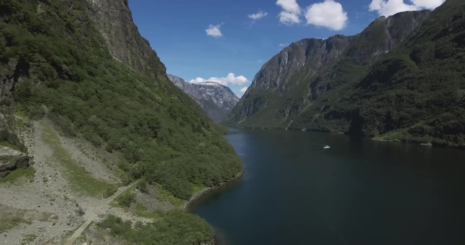 A boat drives on a lake surrounded by vast mountains