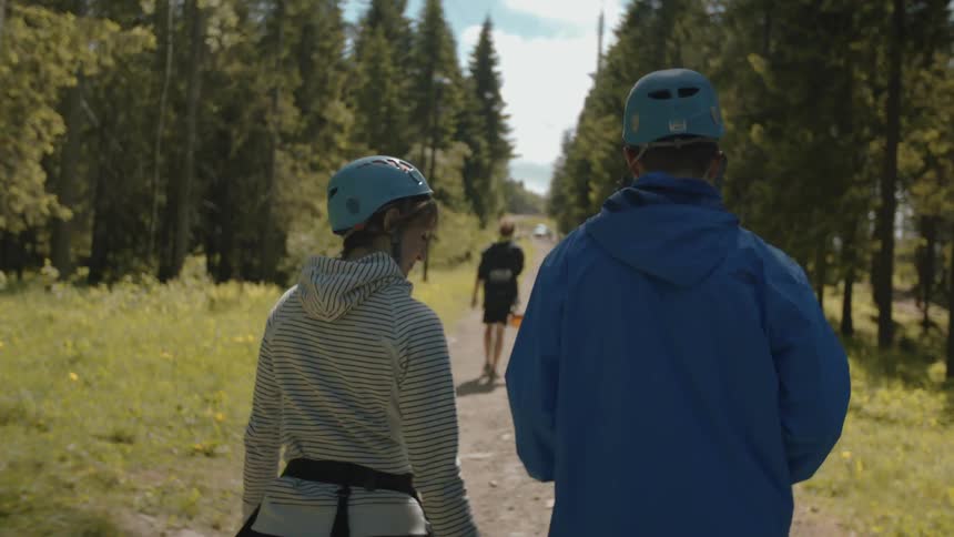 Man and woman wearing helmets walking down a dirt path