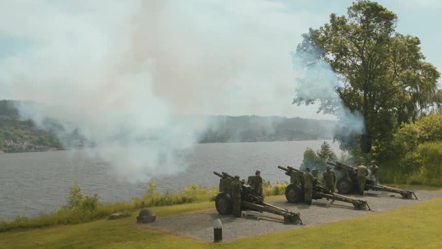Men in uniform fire off mortars from large, stationary guns