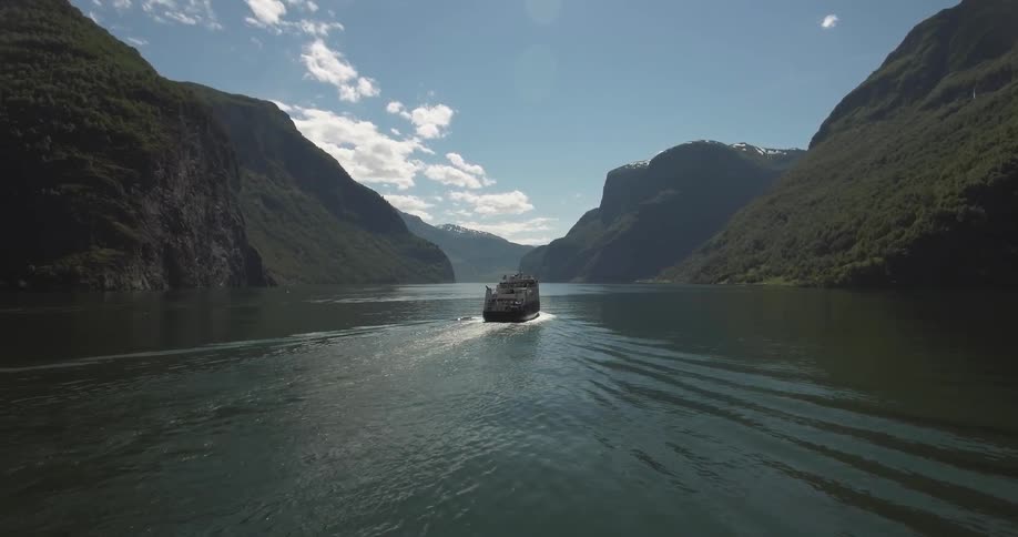 A large boat moves up a fjord