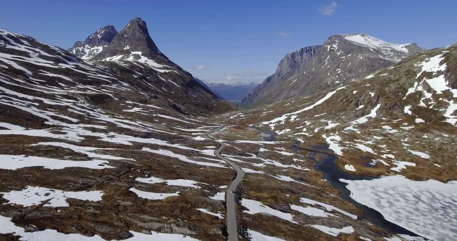 A car drives toward mountains on a winding road