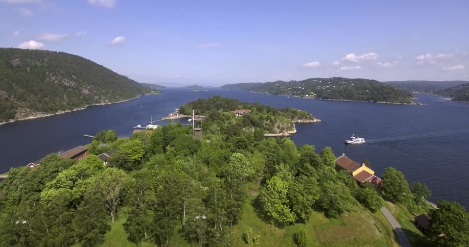 Hills covered with trees and some homes near the water