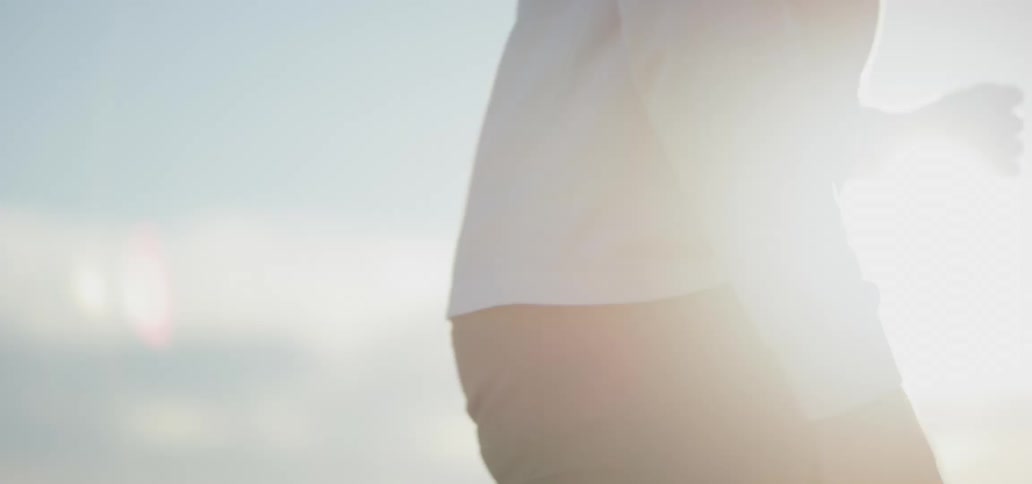 Flare of sunlight shines onto a man who bounces to the right and shifts around outdoors