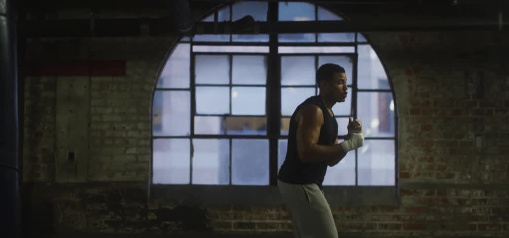 A man is practicing boxing skills with his hands wrapped indoors