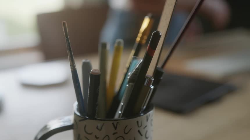 A coffee mug filled with writing utensils on a table