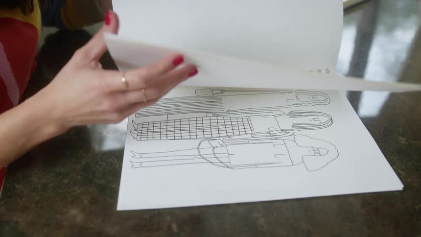A woman is looking at drawings in a notebook
