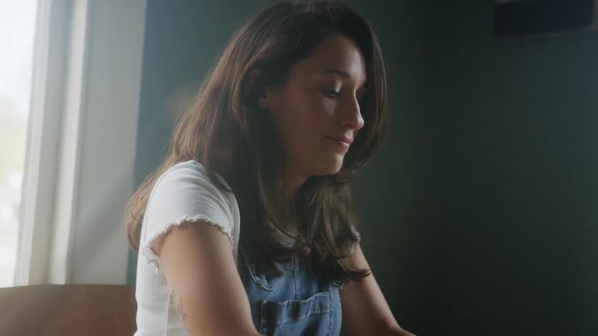 A woman is sitting in her room during the day