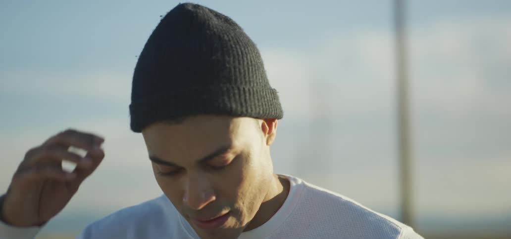 Young man wearing a black beanie standing outdoors at evening