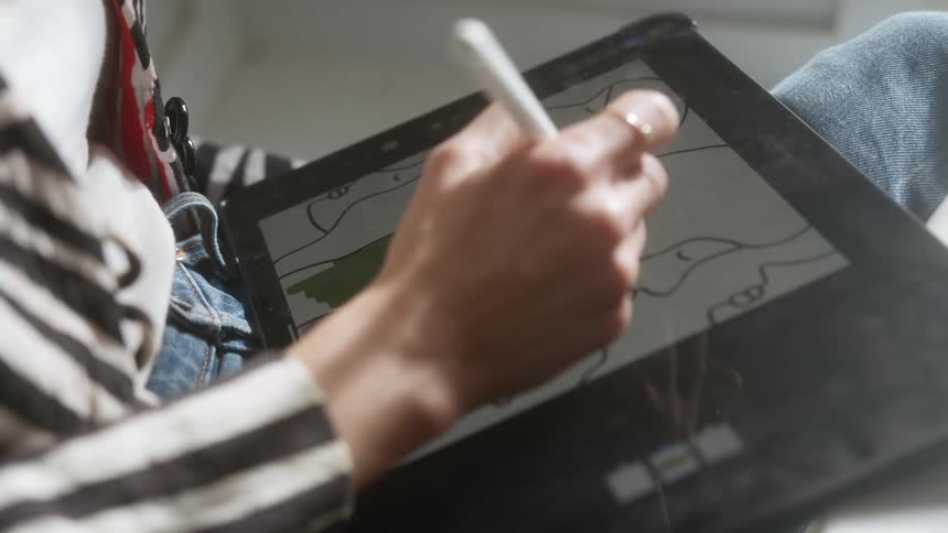 Girl coloring on a computerized drawing tablet with a stylus in her hand