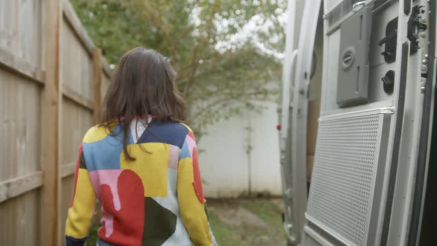 A woman walks and gets in to a trailer