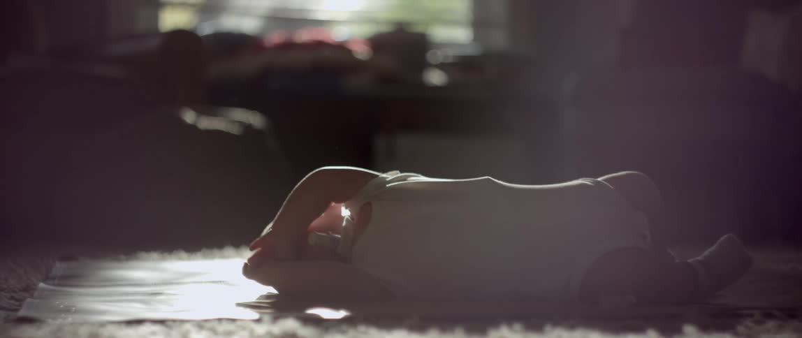 A young baby lies on the floor at home