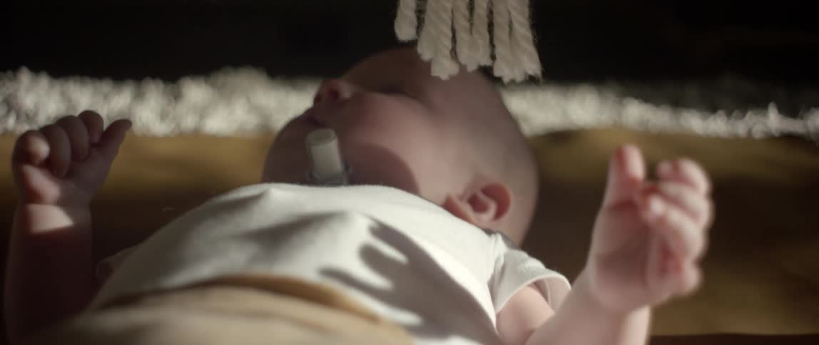 Baby boy with a breathing tube in his throat lying on a bed