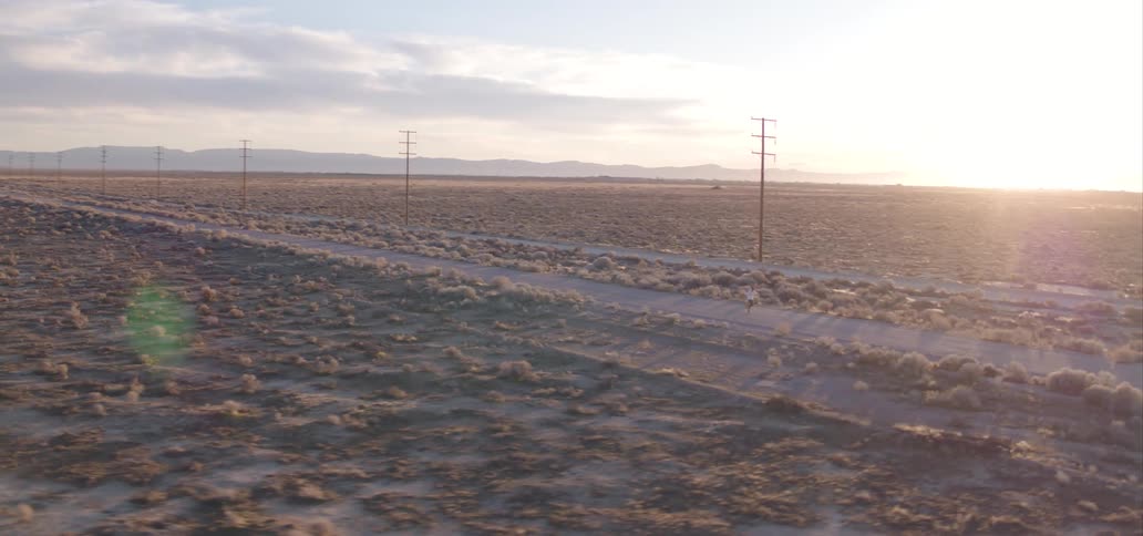 Man jogging and shadowboxing in a rural road through the plains at sunset