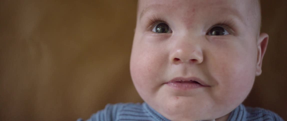 A baby waves his arms around as he lays down