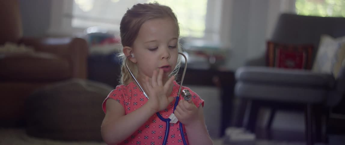 Young girl playing with a stethoscope in the living room at home