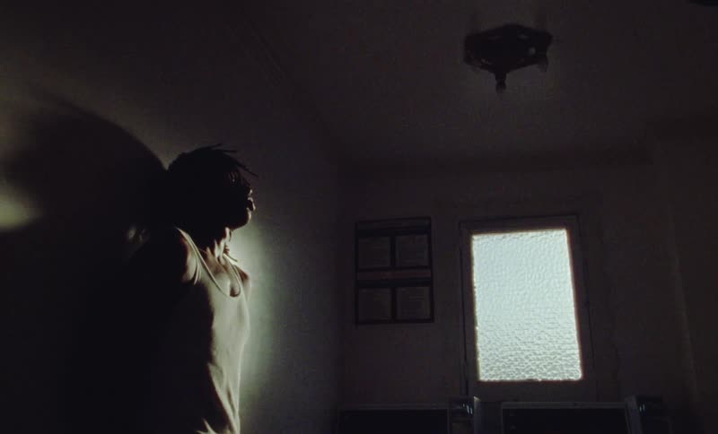 Young fit man wearing a sweatshirt reclined on the wall inside a dimly lit room