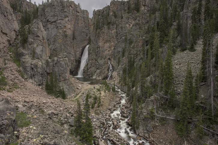 People are hiking by the waterfall