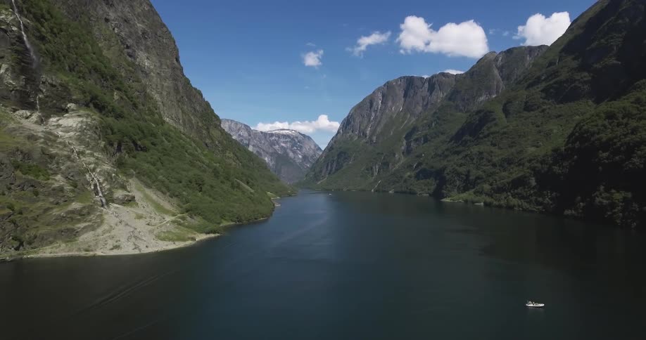 A single boat is in the water by a mountain range