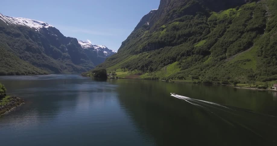 A boat is moving down a lake near a mountain range