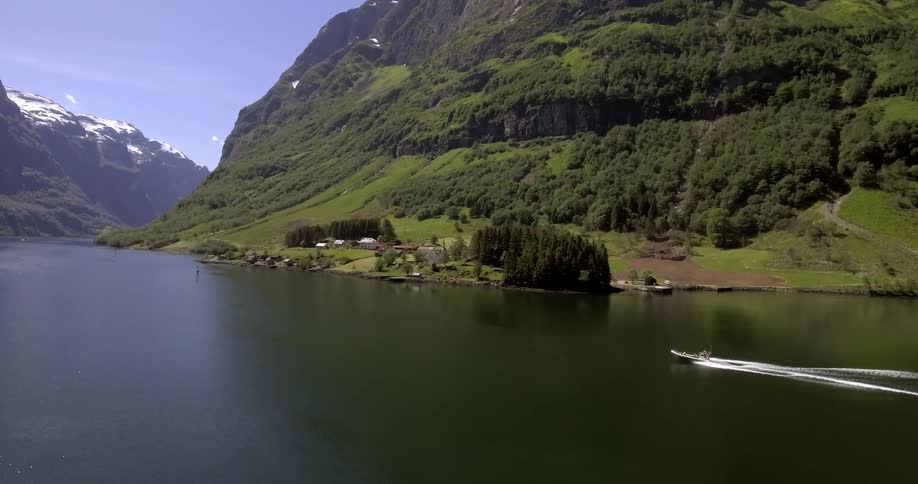 A boat moving through a calm mountainside lake during the day