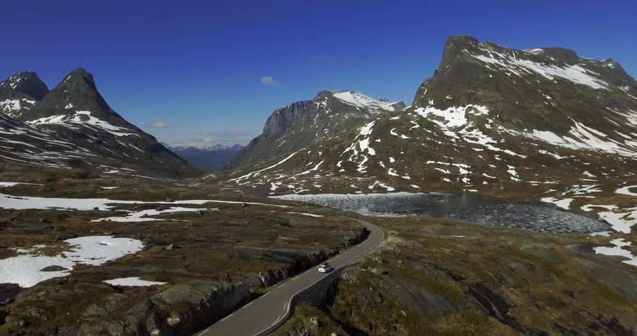 A car drives on a twisting road in the mountains