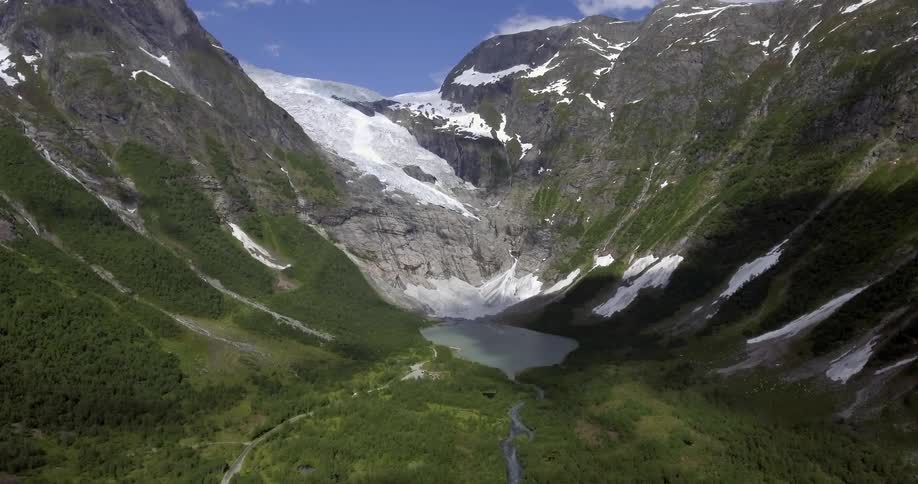 A small lake forms in a valley where melting snow collects from the mountains above