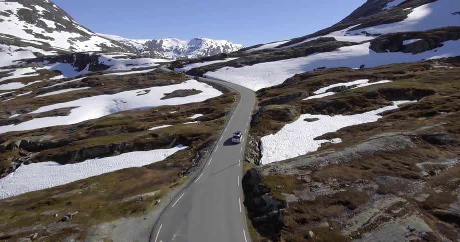 A car is driving along a road on a hillside