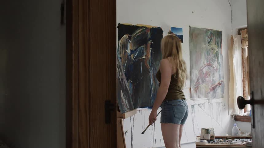 Woman painting a picture that is hanging on a wall