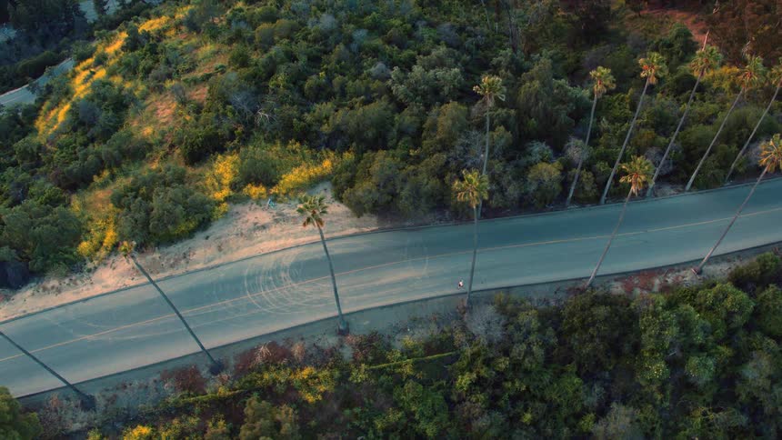 Aerial view of man running down asphalt road in thefield
