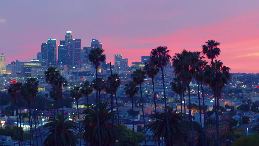 Skyscrapers loom over a metropolis during a colorful sunset